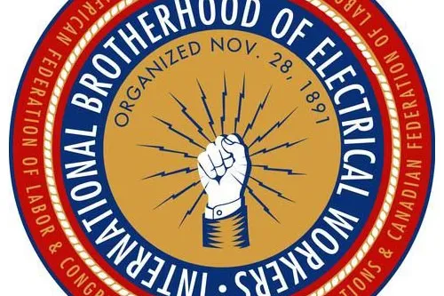 Tan circle with solidarity fist surrounded by lightning bolts surrounded by a blue circle with the white words "International Brotherhood of Electrical Workers." This is surrounded by a red circle with the white words "Affiliated with AFL-CIO and Canadian Federation of Labour."